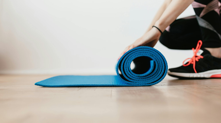 Photo of someone rolling out a Pilates mat